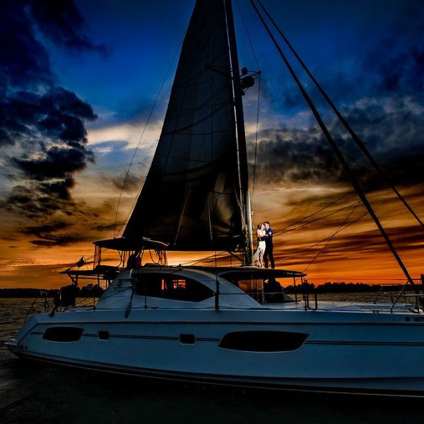 Couple on sailboat at sunset with dramatic sky.