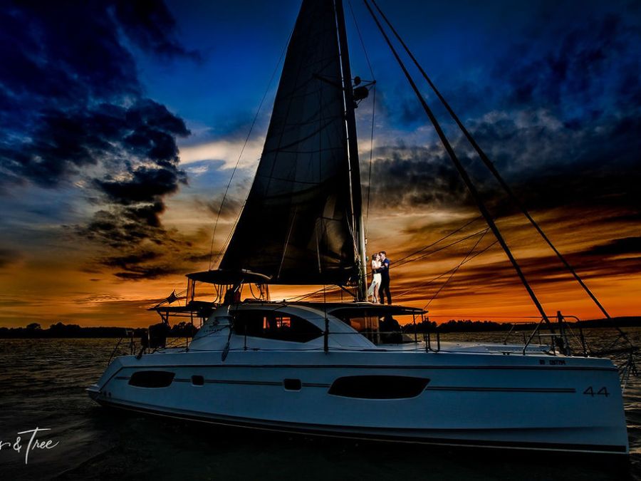 Couple on sailboat at sunset with dramatic sky.