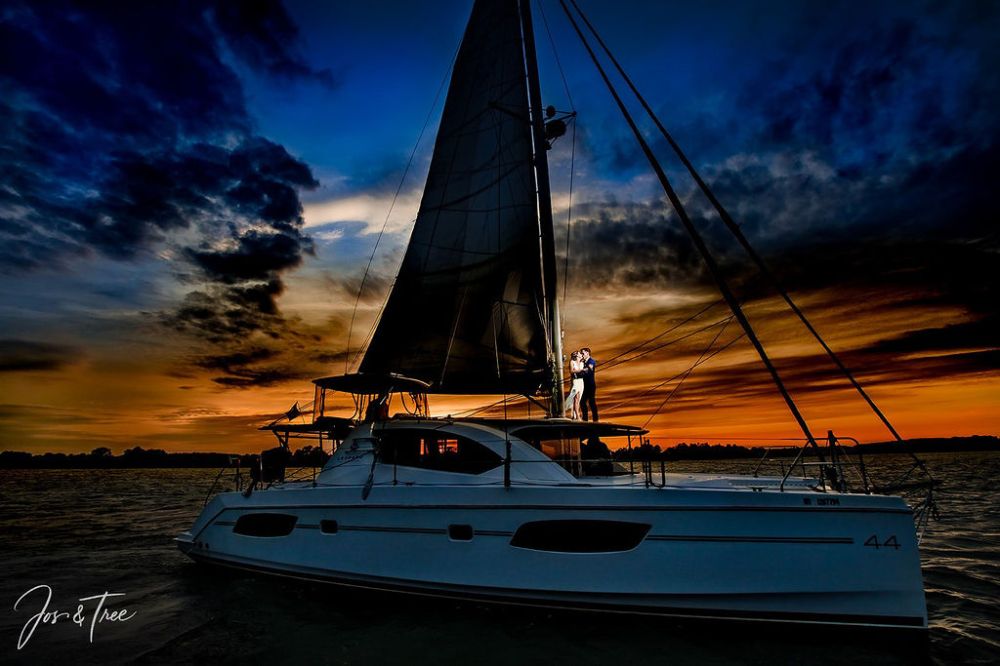 Couple on sailboat at sunset with dramatic sky.