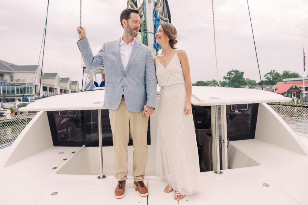 Couple in formal attire holding hands on a yacht deck.