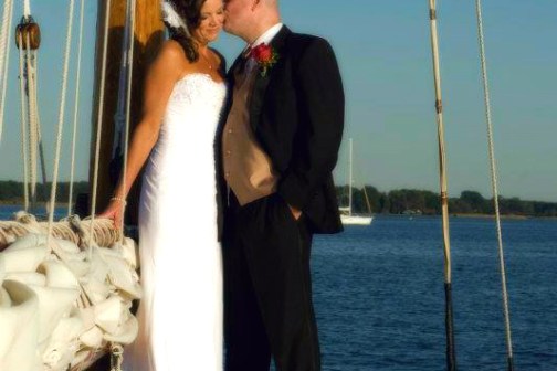 Celebrate love and adventure with Sail Selina, the ideal location for nautical themed weddings and elopements in St. Michaels, MD - This captivating image showcases the loving tenderness between newlyweds as they embark on an unforgettable journey on their boat wedding day - Start your adventure now aboard Sail Selina!