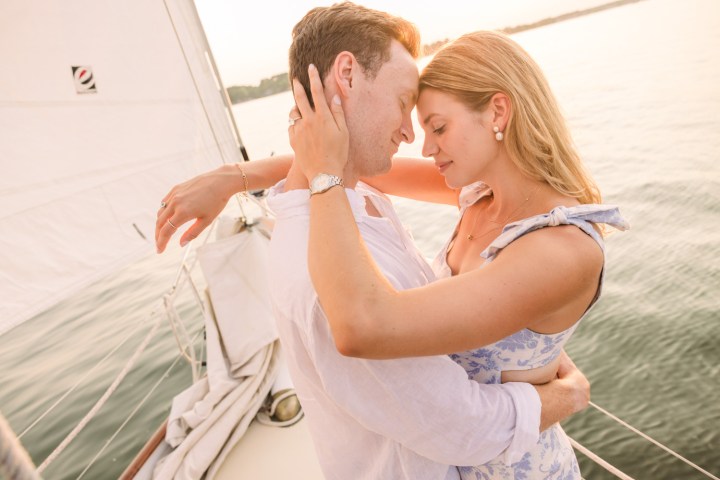 Couple embracing on a sailboat at sunset.