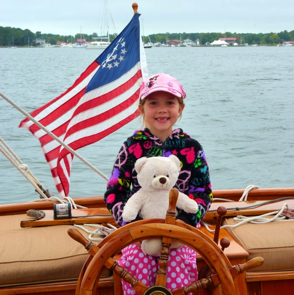Create unforgettable family memories with Sail Selina's family-friendly sailing adventures on the Chesapeake Bay in St. Michaels, MD - This charming image captures the spirit of adventure and wonder, as a little girl and her teddy bear take the helm on Sail Selina's comfortable and well-maintained boat - With our friendly and experienced crew at your side, embark on a journey of exploration and discovery, as you marvel at the beauty of the open waters - Fall in love with Sail Selina's warm and welcoming atmosphere, perfect for family vacations and outdoor adventures - Book now and give your family the gift of a lifetime, a unique and meaningful Sail Selina family sailing adventure!