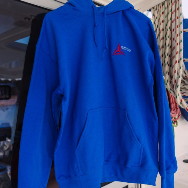 Blue hoodie with a logo hangs on a white hook.