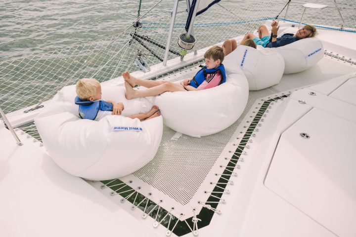 Three people relaxing on bean bags on a boat's deck over water.