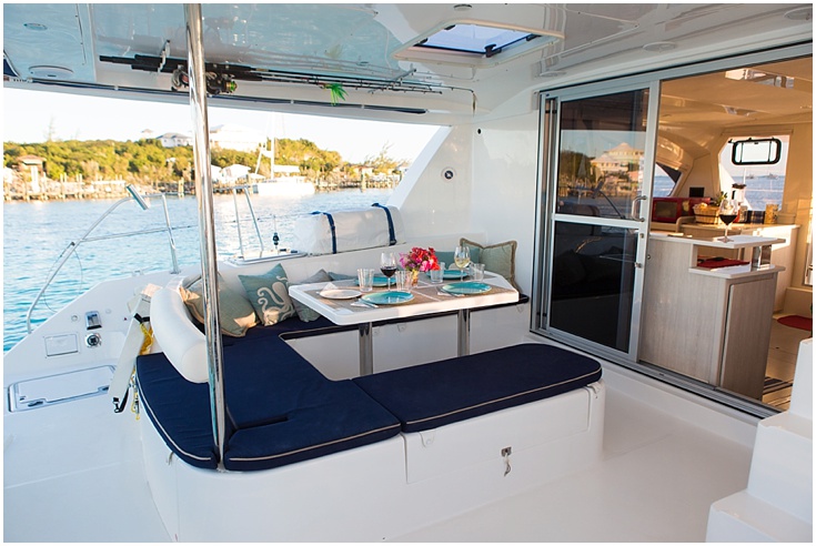 Outdoor yacht dining area with cushioned seats and table set for two, overlooking water and shoreline.