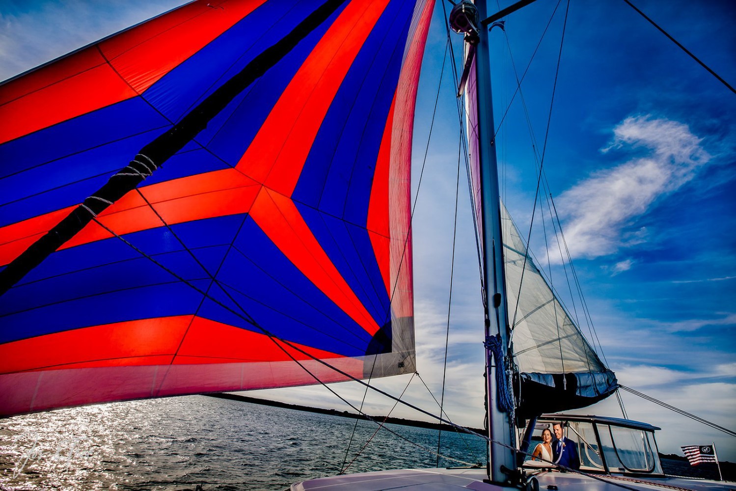 Colorful sailboat with vibrant red and blue sail on a sunny day.