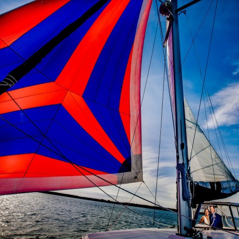 Colorful sailboat with vibrant red and blue sail on a sunny day.