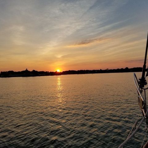 Sailboat on calm water with a vibrant sunset in the background.