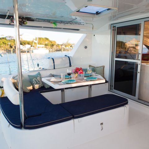 Luxury yacht deck with dining table, seating area, and view of water and shoreline.