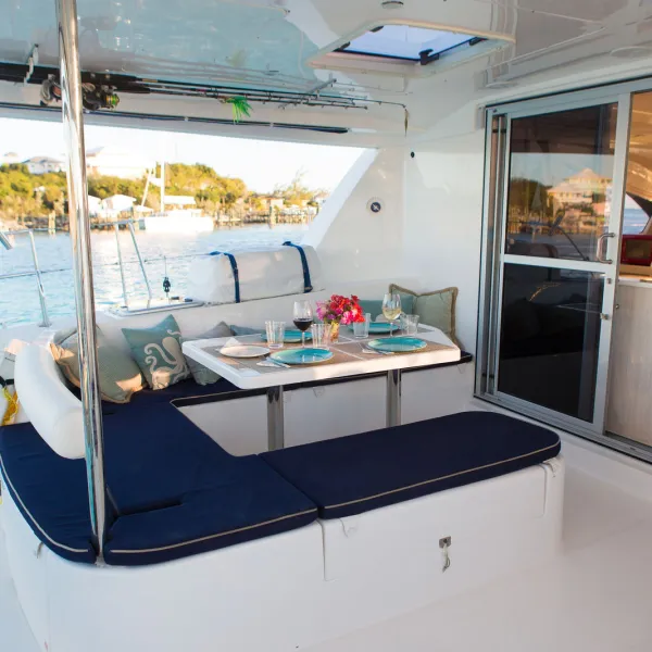 Luxury yacht deck with dining table, seating area, and view of water and shoreline.