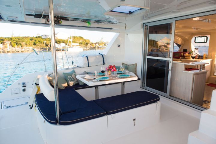 Luxury yacht deck with dining table, seating area, and view of water and shoreline.