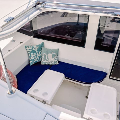 Boat seating area with blue cushions, white tables, and decorative pillows.