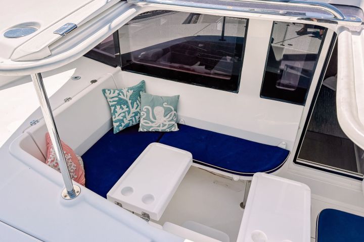 Boat seating area with blue cushions, white tables, and decorative pillows.