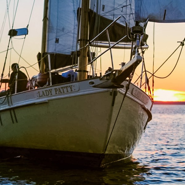 Sailboat named Lady Patty on the water at sunset with sails set.