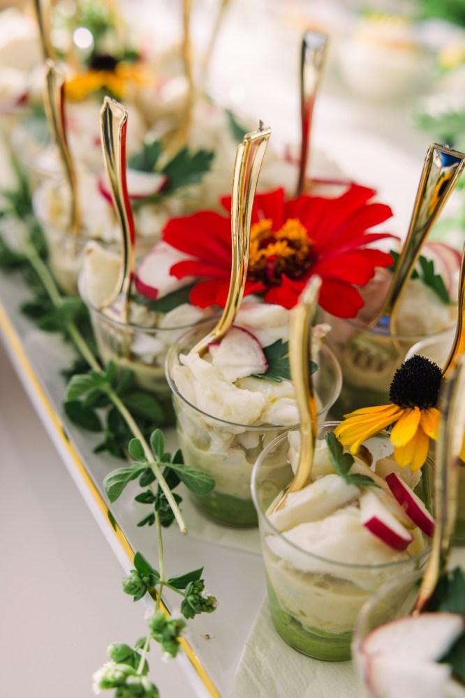 Dessert cups with cream, red flowers, and gold spoons, garnished with greens.