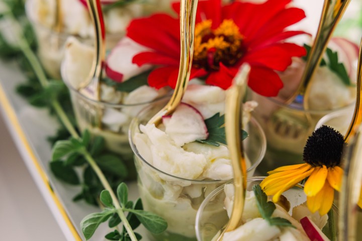 Dessert cups with cream, red flowers, and gold spoons, garnished with greens.