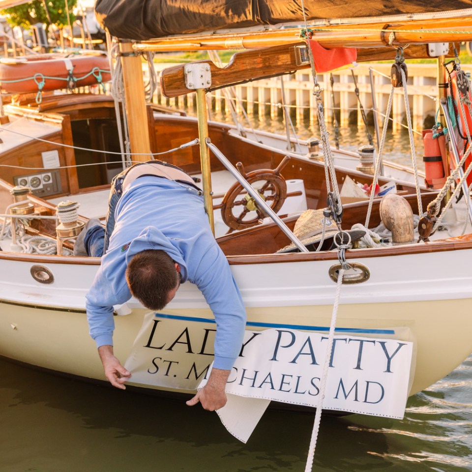 Person attaching a sign to a boat at a dock.