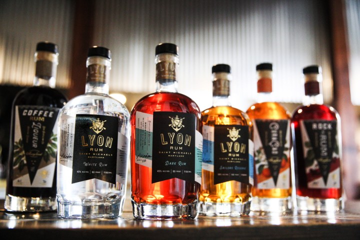 Assorted bottles of rum lined up on a wooden surface.
