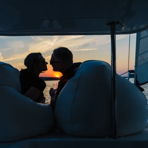 Silhouetted couple kissing on a boat at sunset.