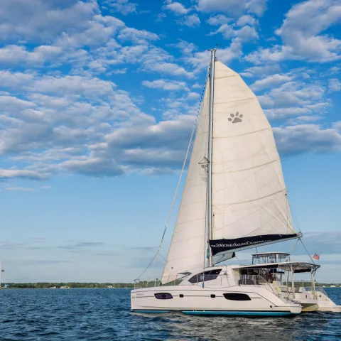 Two sailboats on a serene blue lake under partly cloudy sky.