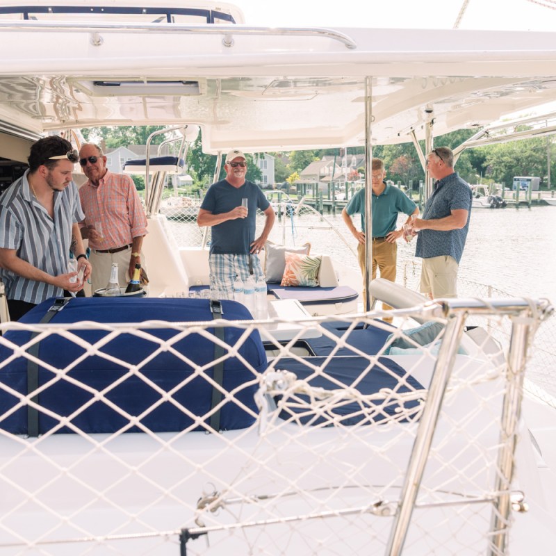 People socializing on a boat deck by the water.