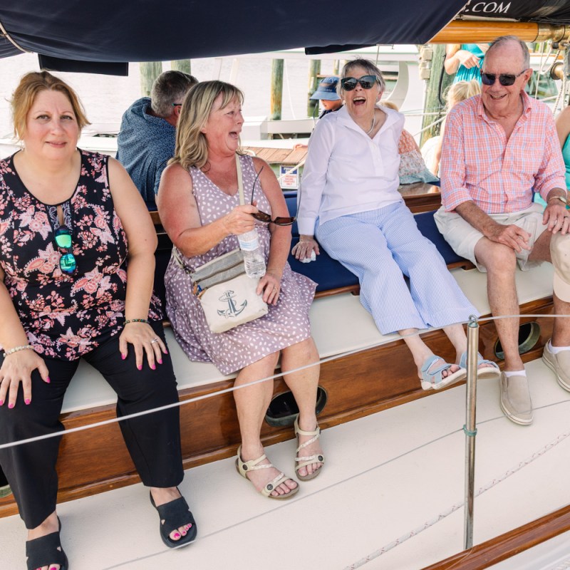 Group of six people sitting on a boat, smiling and chatting.