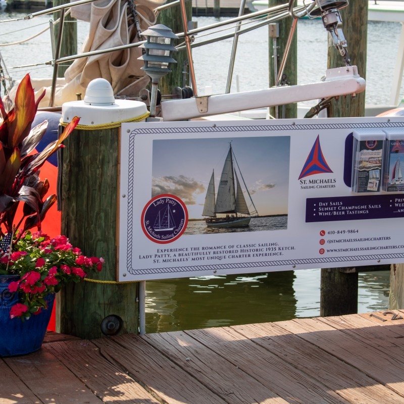 Dockside display with sailboat image and potted plants beside it.