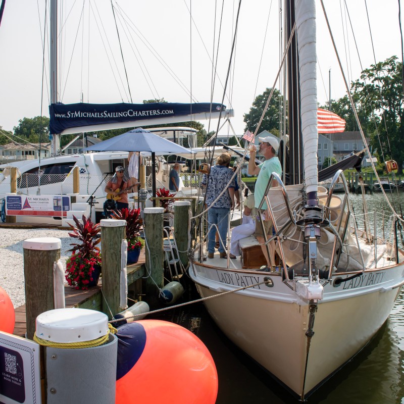 People on a dock next to a sailboat and other boats.